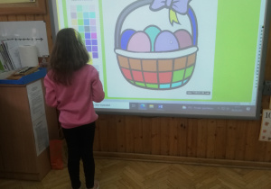 dziewczynka koloruje koszyk na tablicy